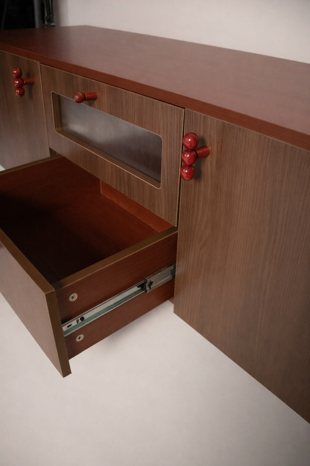 risa-wooden-sideboard-drawer-detail-storage
tv-unit-drawer-slide-storage-detail-red-knobs
modern-wooden-cabinet-drawer-storage-feature-risa