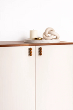 Minimalist cabinet with wooden knobs, marble tray, candle, sculptural knot decor