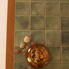 Close-up of green tiled top on wooden coffee table with decorative stones by RISA