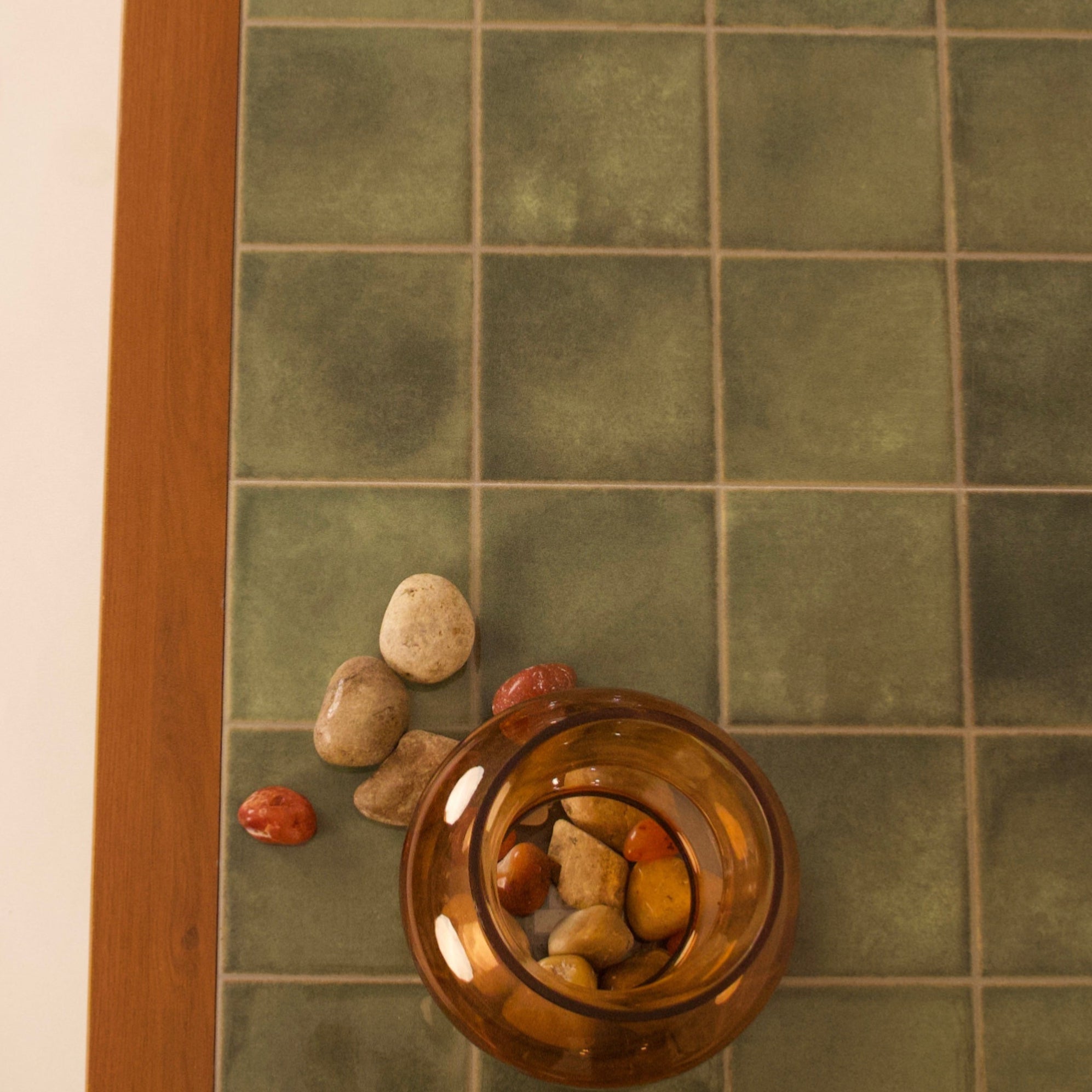 Close-up of green tiled top on wooden coffee table with decorative stones by RISA