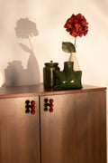 Wooden sideboard with red knobs styled with ceramic vases and flowers by RISA